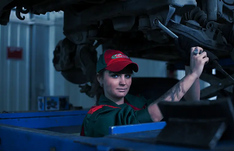 A professional automotive technician working under a lifted vehicle, representing the efficiency and precision that an automotive aftermarket ERP system can bring to inventory management and operations.